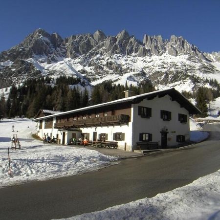 Eine Berghütte liegt in der verschneiten Landschaft, mit Berggipfeln im Hintergrund