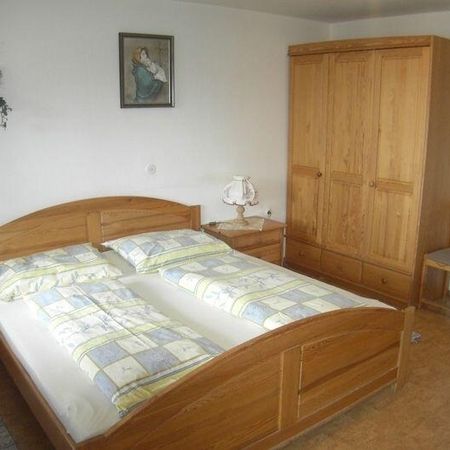 Gemütliches Schlafzimmer mit einem Holzbett mit gemustertem Bettzeug, einem Nachttisch mit Lampe und einem Kleiderschrank